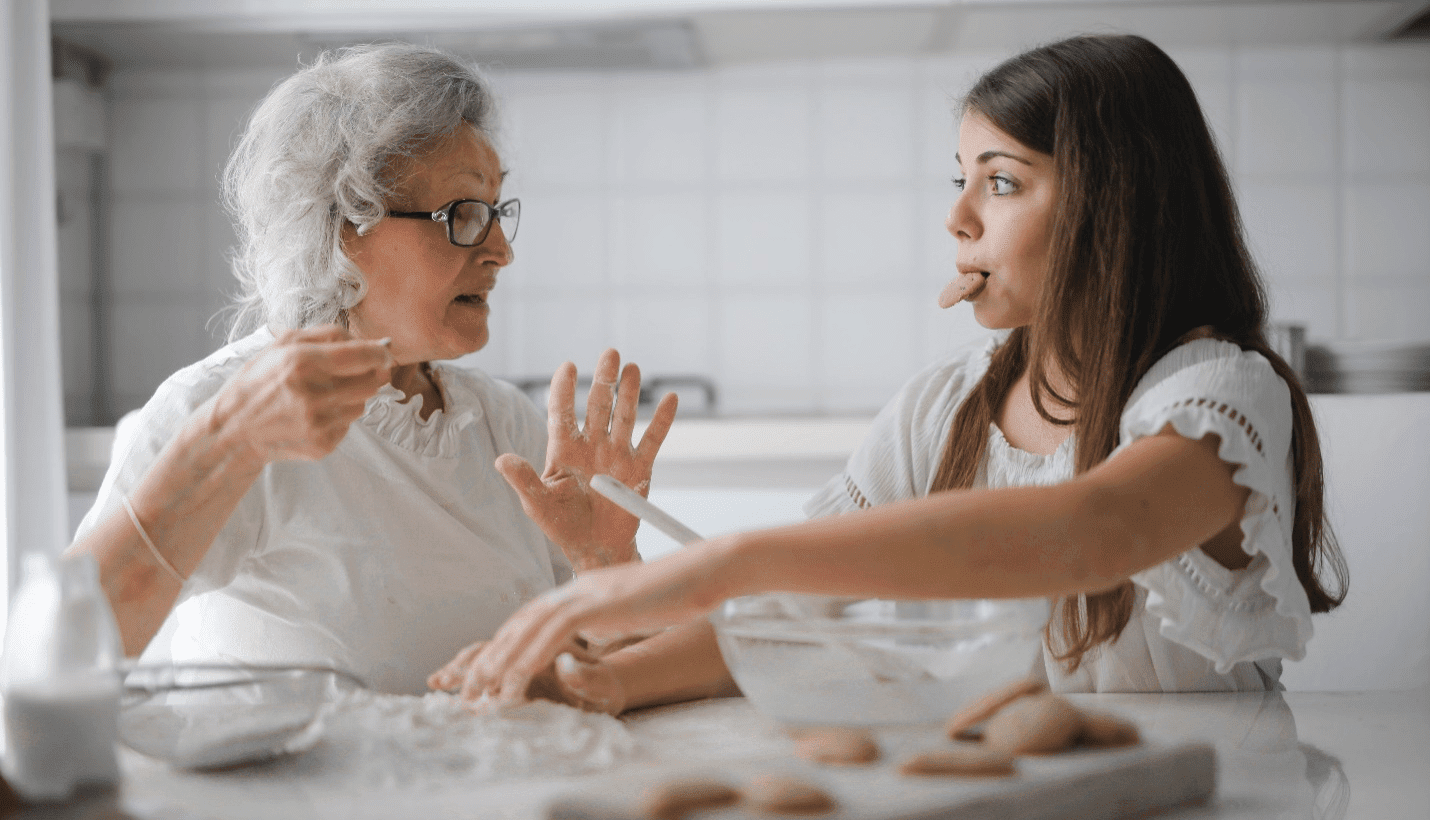 An old woman baking with a teenage girl.