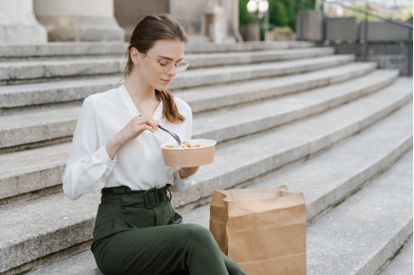A woman in a white blouse sitting on the stairs with a bowl of food